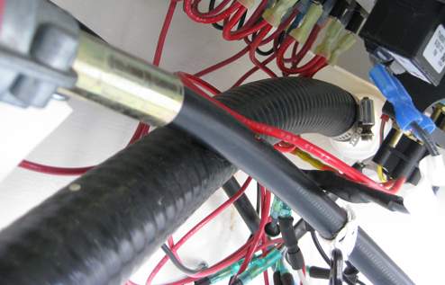 The discharge hose leads up and under the steering consol to the side of the cockpit