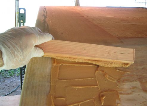 Using a 2 x 2 to spread putty on bottom of boat