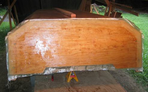 I took a disposable paint brush and daubed epoxy 
resin on various spots across the cloth on the transom, and then took a soft plastic spreader with a 5-inch blade and spread the epoxy around