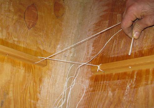 I am using a piece of scrap wood as a fid to 
thread the rope through the holes in the mounting blocks