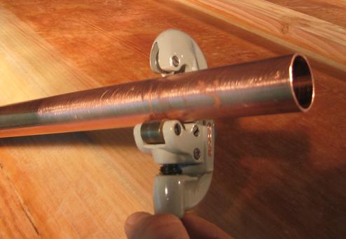A one-inch copper pipe is being cut to size for the transom drain pipe